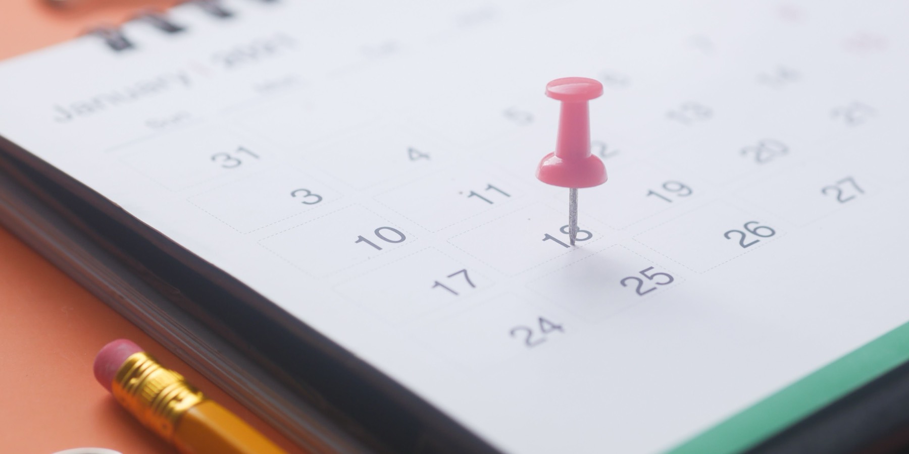 A wall calendar with a pin marking a date, seen close up.
