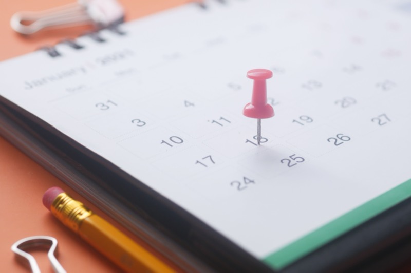A wall calendar with a pin marking a date, seen close up.