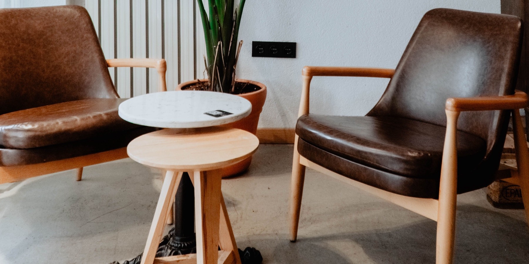 Two leather armchairs facing a small table in a quiet, light-filled room.